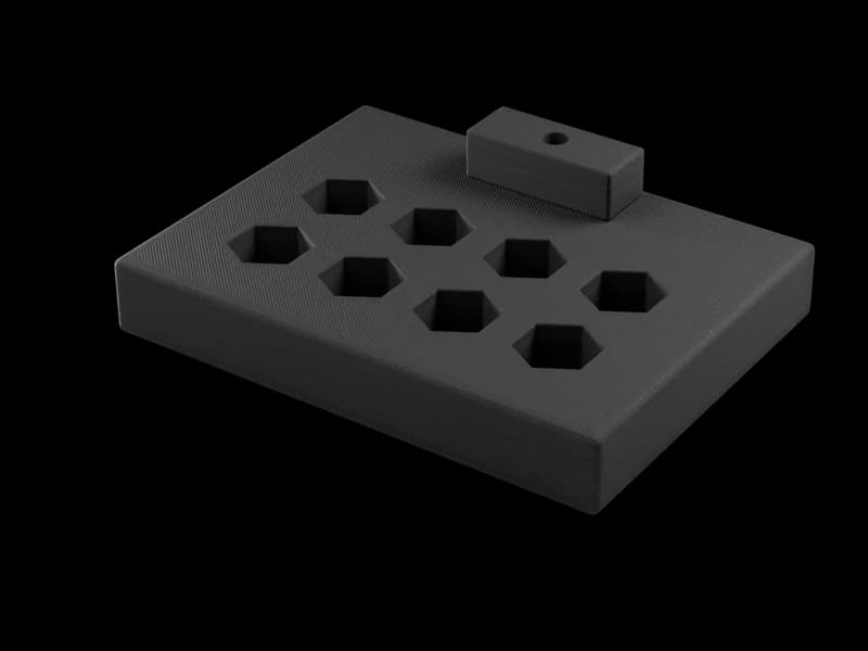Render of a black printed fixture plate with hexagon pockets and a printed clamp block