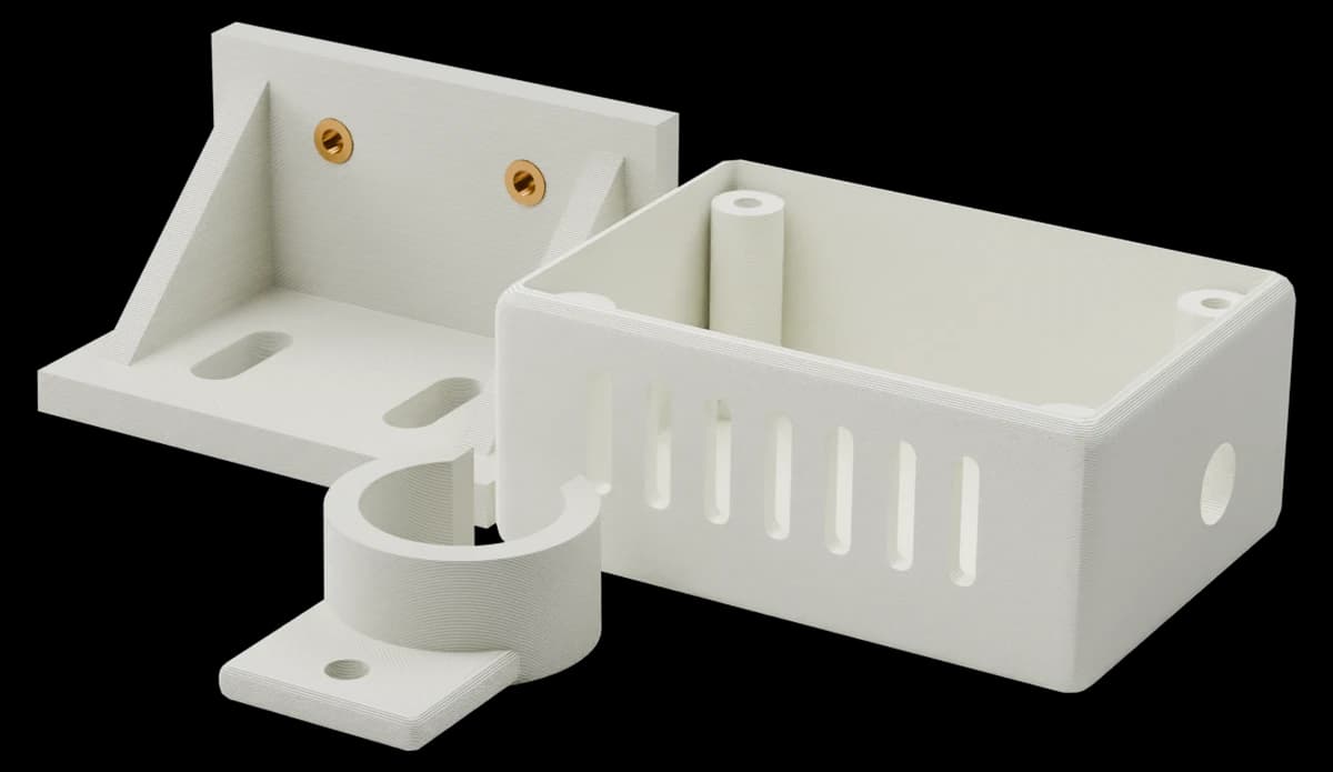 Render of three white PETG parts grouped together: an open electronics enclosure, an angle bracket with threaded inserts and a pipe clip, with printed layers visible