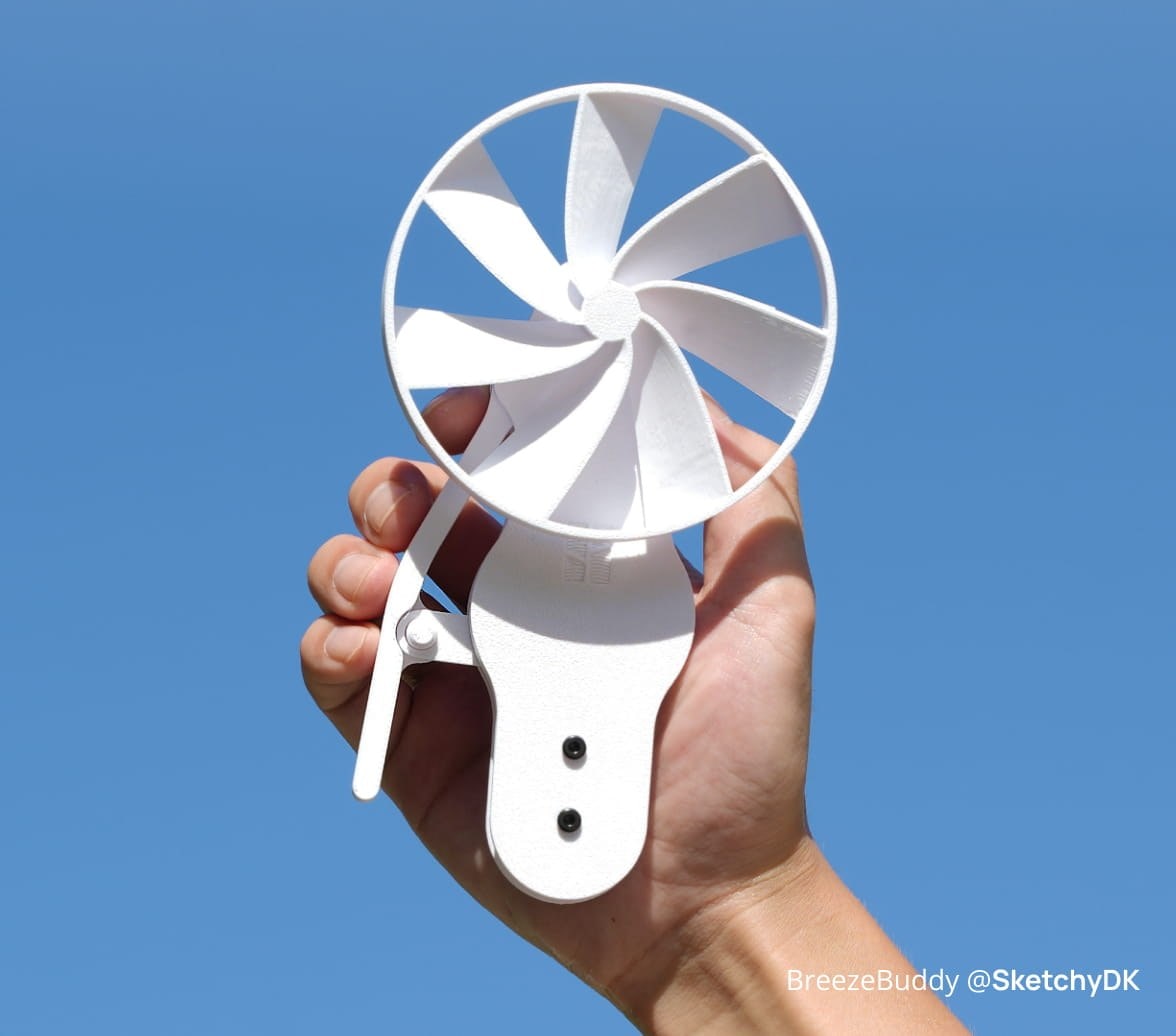 A white handheld fan with a printed mounting bracket, held up against a blue sky