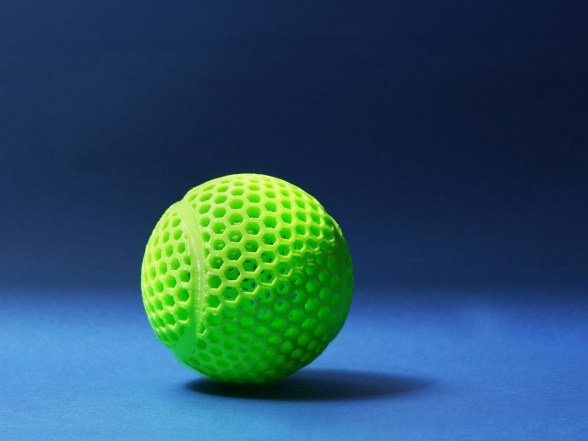 A squeezable green TPU lattice ball on a blue surface